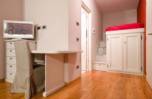 foto secondaria della camera Camelia con una sedia e una scrivania con sopra una televisione. In secondo piano il letto a soppalco